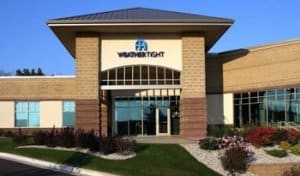 Image shows the exterior of the Weather Tight showroom, with landscaping in front and a blue sky behind.